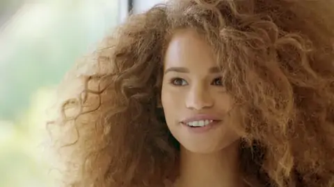 Nubile black with wavy hair is railing a enormous lollipop on the bed